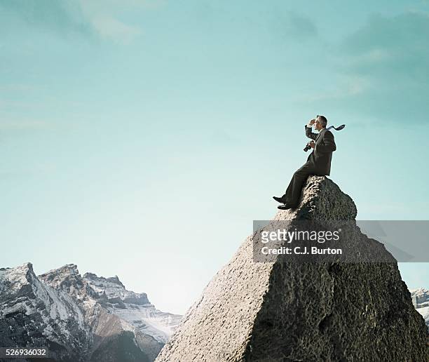 businessman sits on a mountain searching - leading edge stock pictures, royalty-free photos & images