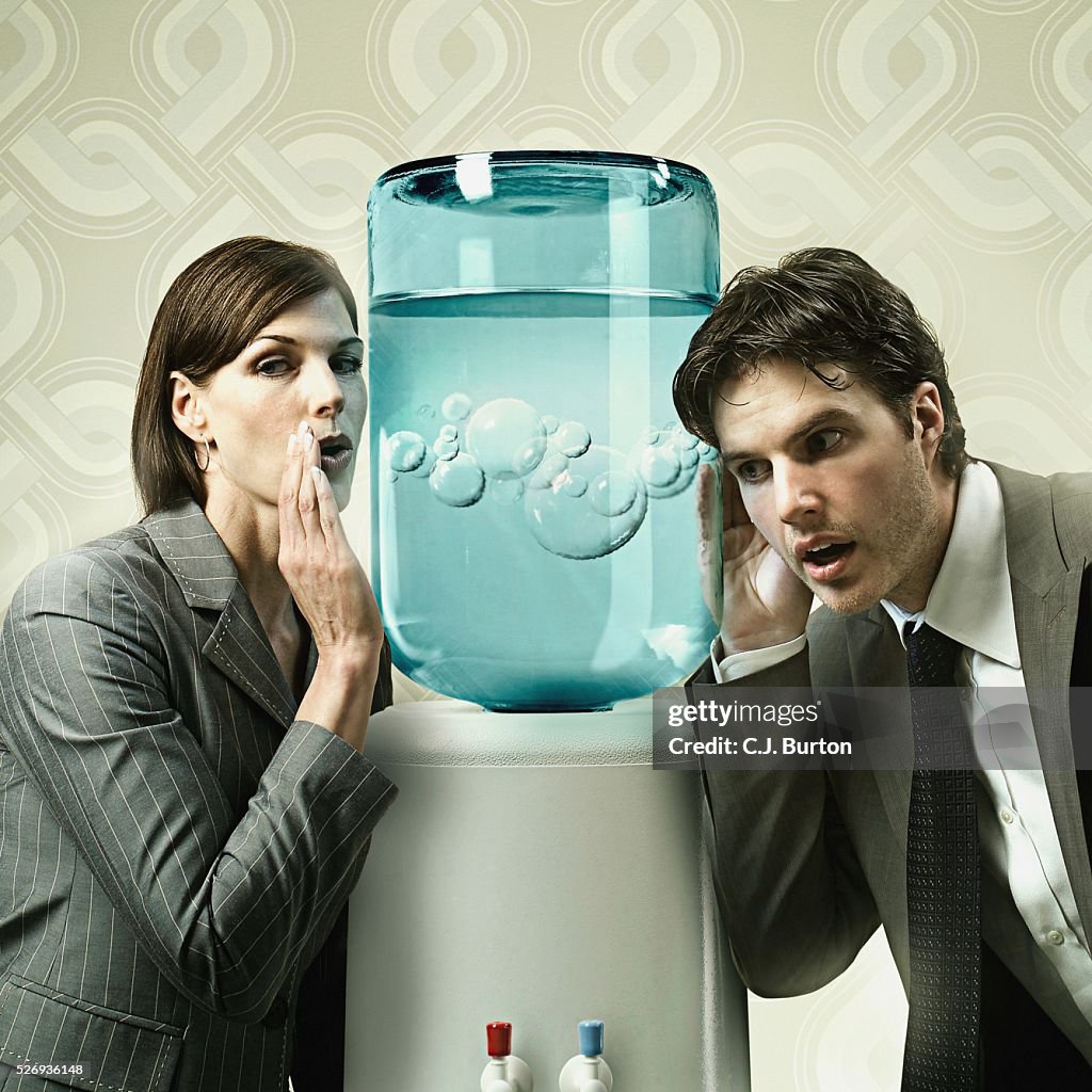 Businesswoman whispering into a water cooler