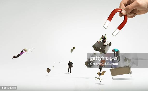 giant hand and magnet picking up office and workers - magnet foto e immagini stock