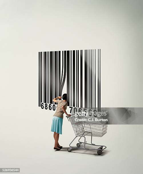 woman with shopping cart looking inside giant barcode - shopping cart stock-fotos und bilder