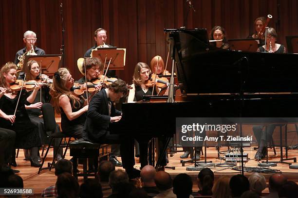 English pianist Benjamin Grosvenor directs while playing the piano the Britten Sinfonia with violinist Jacqueline Shave beside him in a performance...