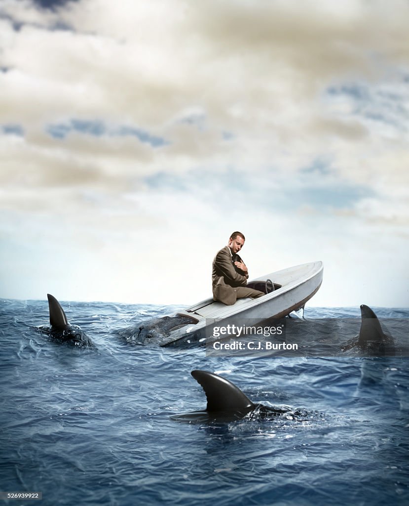 Sharks surrounding man sitting in sinking boat