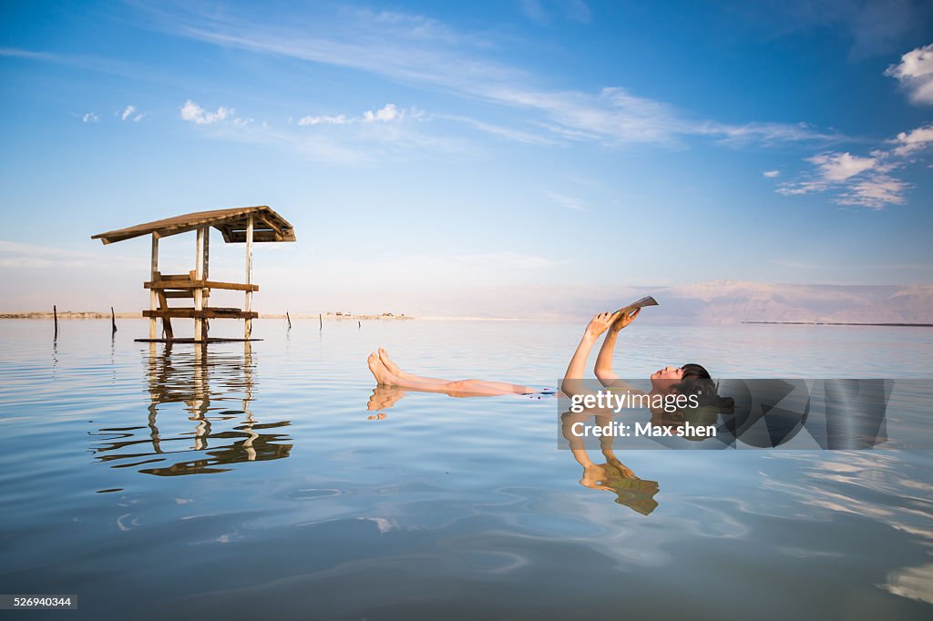 Tourist floating reading in Dead Sea in Israel