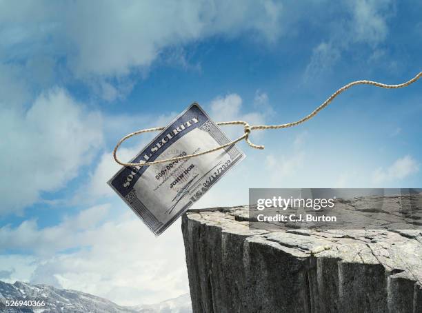 social security card is teetering on side of cliff - sozialversicherung stock-fotos und bilder