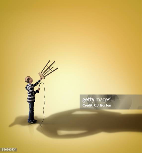 boy holding stool and whip up to shadow of very large bully - uneven stock pictures, royalty-free photos & images
