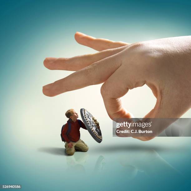 boy hiding behind shield from larger hand that is about to flick him - aggression studio stock-fotos und bilder