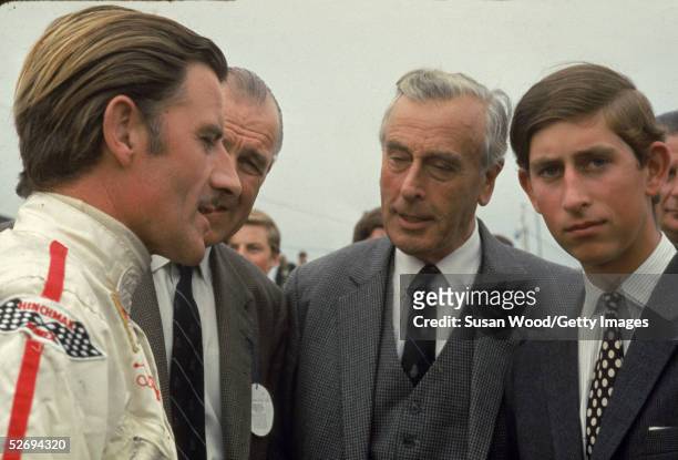 British race car driver Graham Hill talks with Lord Louis Mountbatten and Prince Charles, Prince of Wales.