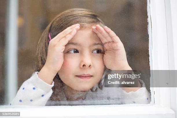 cute little girl looking outside window - peep window stock pictures, royalty-free photos & images