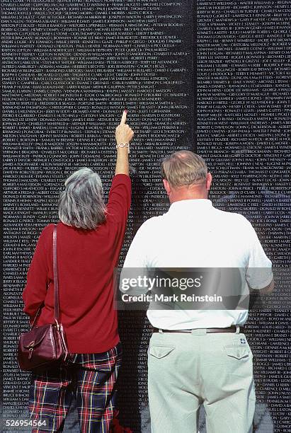 Washington DC. Vietnam Veterans Memorial Wall. A couple of tourists point out to themselves the names of friends or sons lost in the conflict know as...
