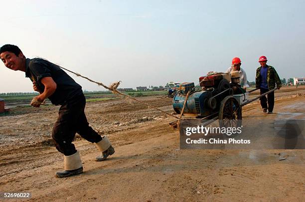 Migrant workers remove an engine at a highway construction site on April 25, 2005 in Feidong County of Anhui Province, East China. There has been a...