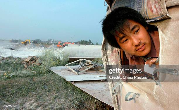 Migrant worker looks out of a shelter he lives in at a highway construction site on April 25, 2005 in Feidong County of Anhui Province, East China....