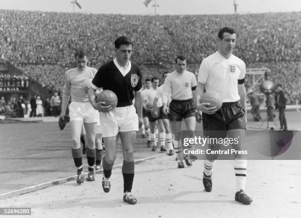 The England and Scotland captains, Johnny Haynes and Eric Caldow respectively, lead their teams onto the pitch at Wembley at the start of the...