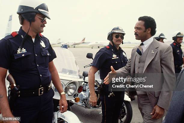 Jesse Jackson, Baptist minister and candidate for the Democratic presidential nomination in 1984, greets members of his police motorcycle escort...