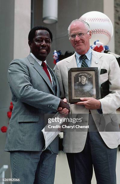 Baseball commissioner Bowie Kuhn shakes hands with Hank Aaron as he presents him with a plaque upon Aaron's induction into the Baseball Hall of Fame.