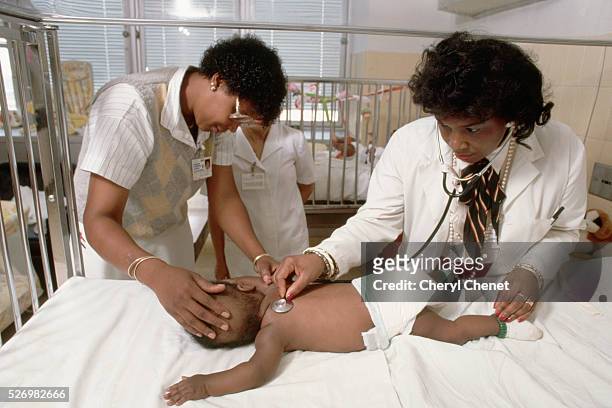 Physician checks a positive baby's breathing with the assistance of a nurse.