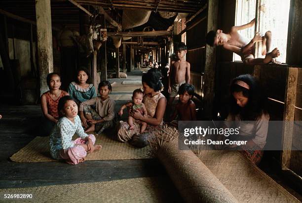 An Iban woman weaves a mat in the corridor of a longhouse. | Location: Buau village, Brunei.