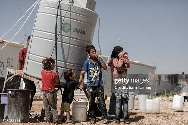 Hamoudi and his brother Mahmoud, 2 from Ghouta, near Damascus in Syria, collect drinking water from a water tank in Zataari camp in Jordan, which is...