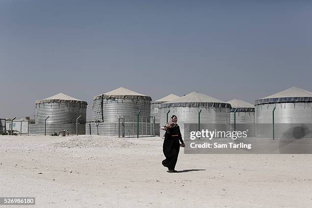 Woman walks past huge water tanks in district 6 of Zataari camp in Jordan, which is home to around 80,000 Syrian refugees. Half of the camp's...