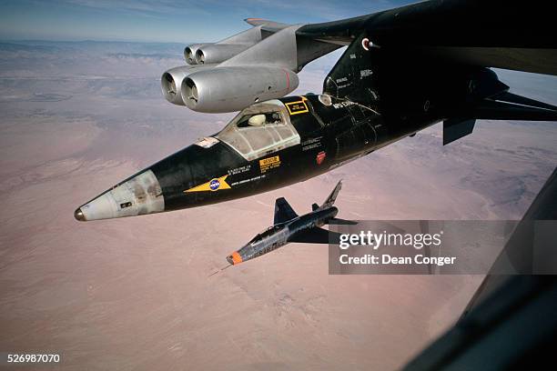 Carries an X-15 rocket plane under its wing, to launching altitude for a test flight over Edwards Air Force Base in California. A chase plane follows...