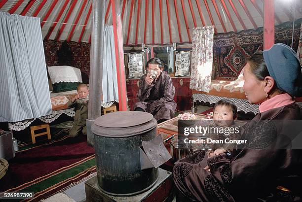 Mongolian truck driver and his family relax in their yurt around a stove. Their yurt stands permanently in Ulan Bator, the capital city of Mongolia,...