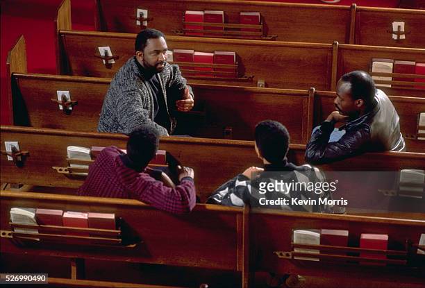 Christian pastor, Harvey Drake, talks to several young men, co-workers, in a pew of the church. Drake is the director of the Emerald City Outreach...