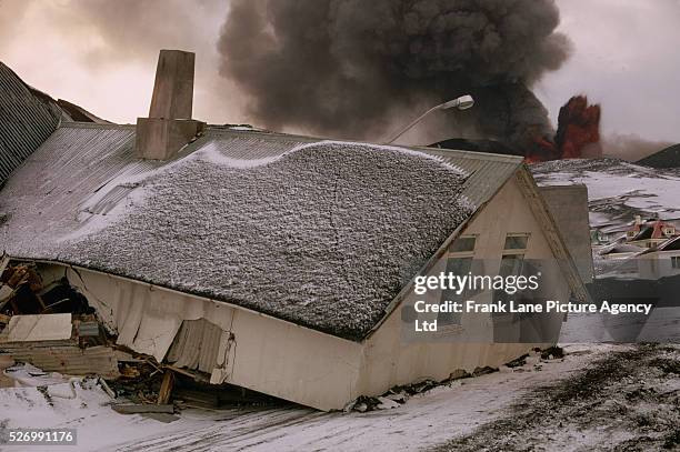 Houses engulfed by lava and ash pushed into the street following an eruption of Heimaey Volcano. Ash and lava continue to belch from the volcano...