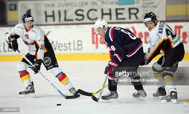 John-Michael Liles of the USA breaks through against Lasse Koptiz and Daniel Kreutzer of Germany during The International Friendly Ice Hockey match...