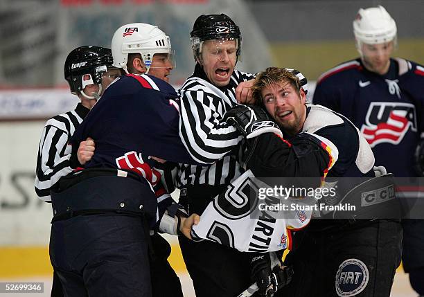 Jeff Halpen of the USA is separated by the referee from Thomas Martinec of Germany during a fight at The International Friendly Ice Hockey match...