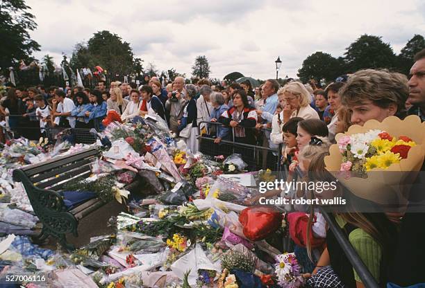 Mourners stand behind a pile of flower bouquets lying against a temporary barricade outside Westminster Abbey on the day of Princess Diana's funeral,...