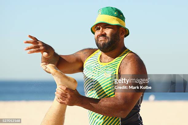 Sam Thaiday brushes sand of the foot of Cooper Cronk during stretching at the Australia Kangaroos Test team recovery session at Coogee Beach on May...