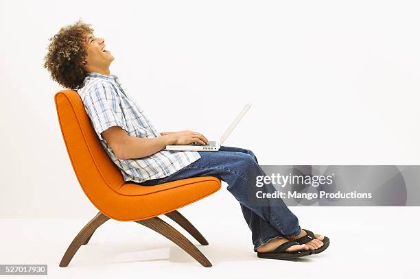 young laughing man using laptop - profile laptop sitting stock pictures, royalty-free photos & images