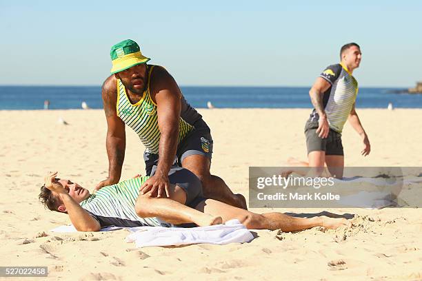 Sam Thaiday assists Cooper Cronk during stretching at the Australia Kangaroos Test team recovery session at Coogee Beach on May 2, 2016 in Sydney,...