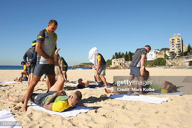 Blake Ferguson assists Josh Dugan during stretching at the Australia Kangaroos Test team recovery session at Coogee Beach on May 2, 2016 in Sydney,...