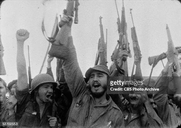Screen capture of Cuban guerilla leader and future dictator Fidel Castro and associates as they cheer and raise their weapons and fists in the air on...