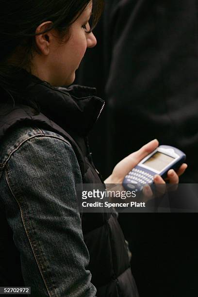 Woman responds checks messages on her Blackberry-hand held device April 27, 2005 in New York City. According to the American Society of Hand...