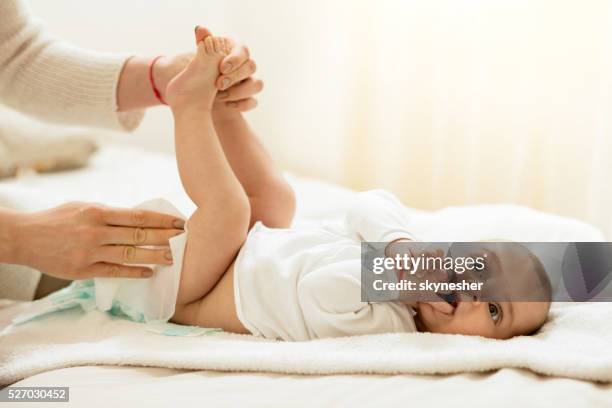 niedlich baby im schlafzimmer erste windel geändert. - mum changing nappy stock-fotos und bilder