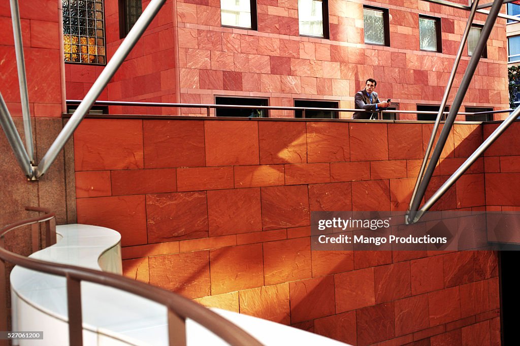 Businessman leaning on a mezzanine railing