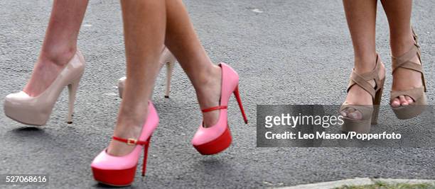 Close up view of three young women wearing high heeled shoes in cream, pink and tan on Ladies Day during The Grand National Meeting at Aintree...
