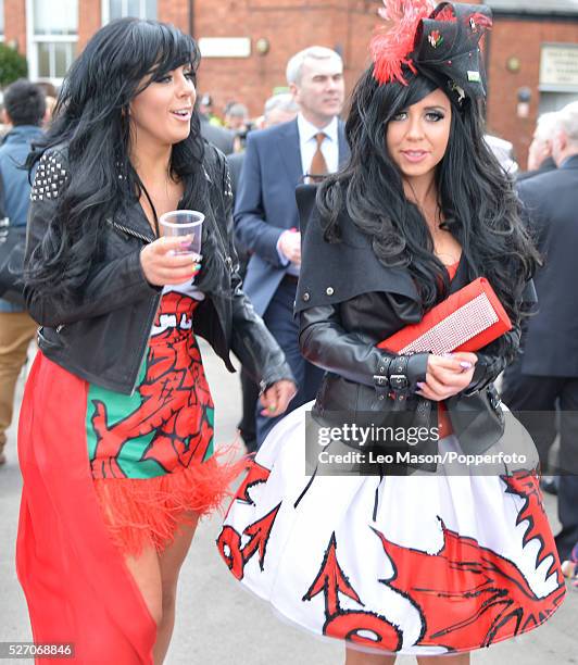 View of two young women, both wearing leather jackets and skirts with a Welsh dragon motif as they attend Ladies Day during The Grand National...