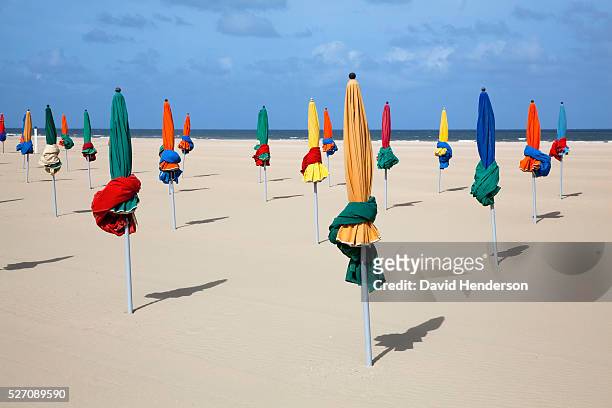 furled beach umbrellas on beach, deauville, france - deauville beach stock pictures, royalty-free photos & images