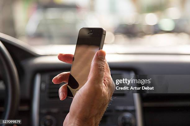 Man driving car and checking the smartphone in first person view.