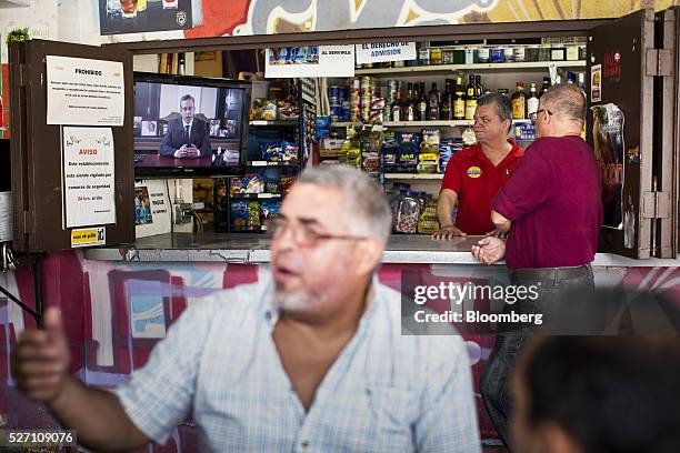 Barman and a customer watch Alejandro Garcia Padilla, governor of Puerto Rico, giving a speech on a television screen in a bar in San Juan, Puerto...