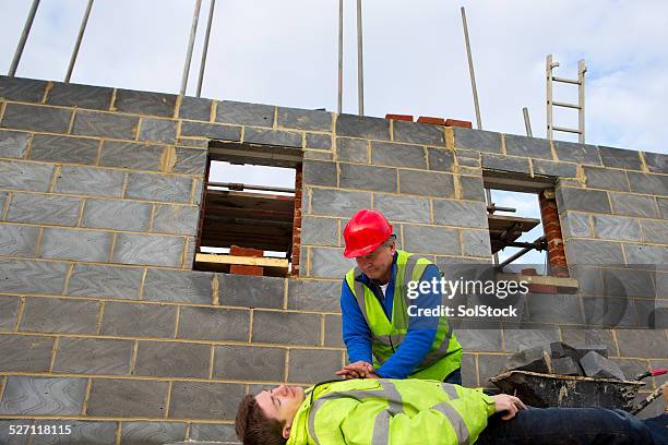 builder giving first aid to an injured colleague - bent ladder stock pictures, royalty-free photos & images