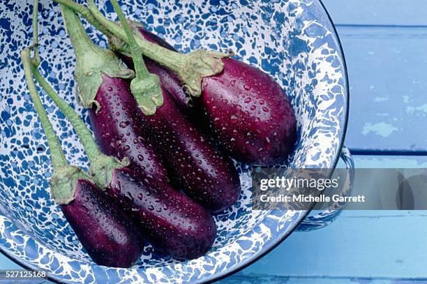 wet eggplants in a blue bowl - aubergine fotografías e imágenes de stock