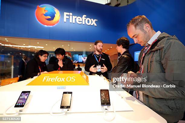 Attendees inspect mobile devices, which run on a Firefox operating system, at the Mozilla Corp. Pavilion during the Mobile World Congress at the Fira...