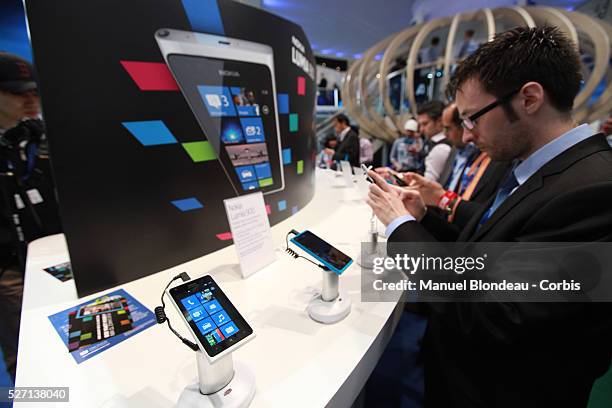 Men check the Nokia Lumia 900 smartphone at the Mobile World Congress in Barcelona on February 29, 2012 on the Third day of the Mobile World...