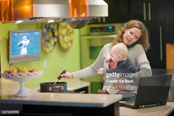 busy mother cooking in kitchen - multitasking stock-fotos und bilder