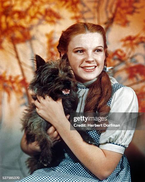 Judy Garland, as character Dorothy Gale, holds Toto in a publicity still for 'The Wizard of Oz'.