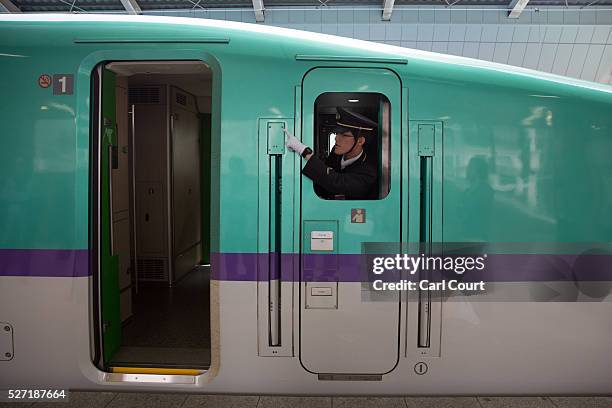 Train guard gestures as he leans out of a window on a Shinkansen bullet train at Tokyo Train Station on May 02, 2016 in Tokyo, Japan. The Shinkansen...