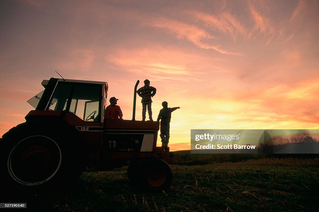 Farmer and his sons watching the sunset